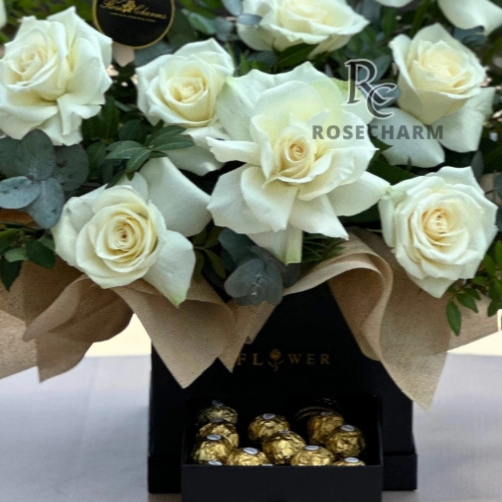 Arrangement of white roses and chocolates in a box