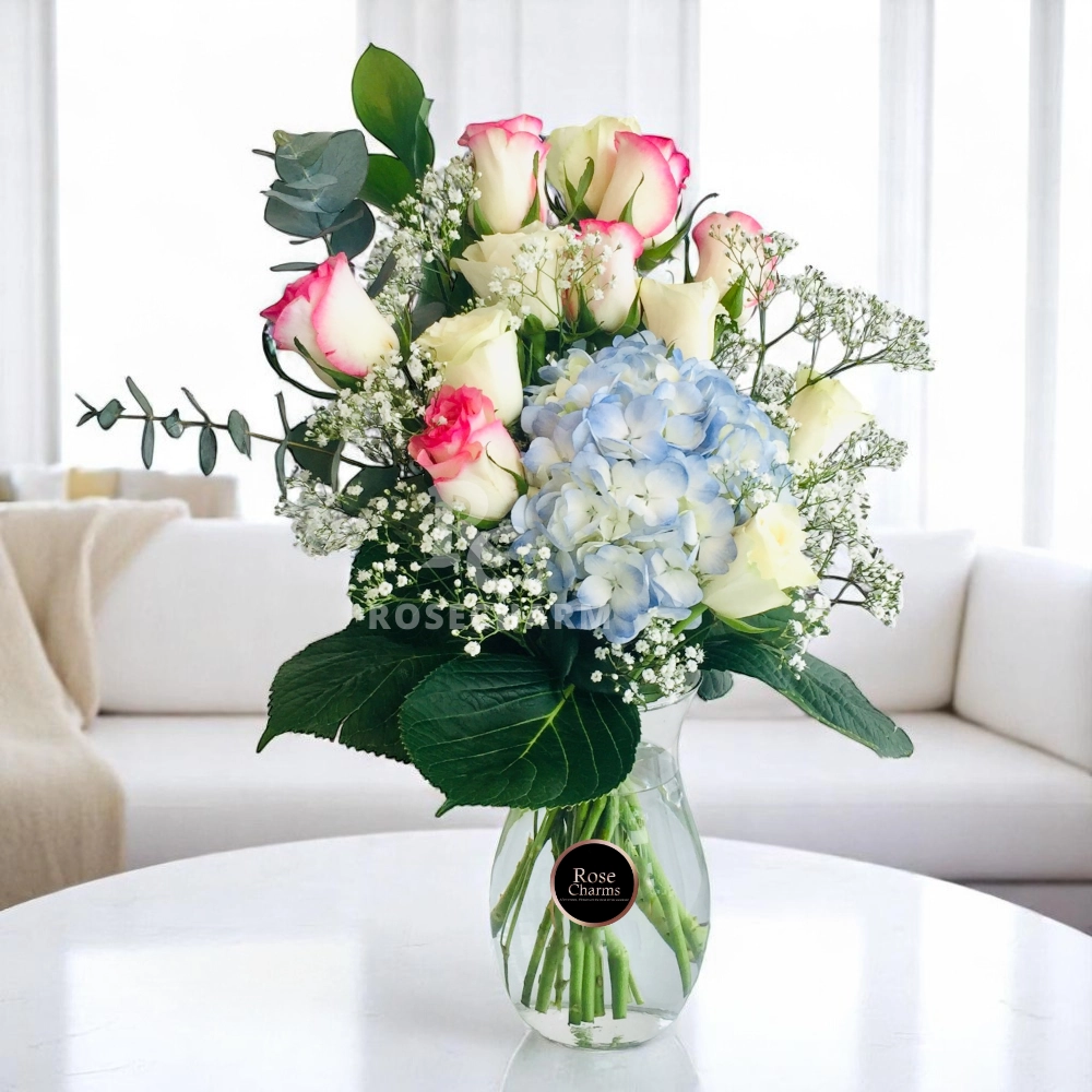 Arrangement of blue hydrangea, roses in a glass vase